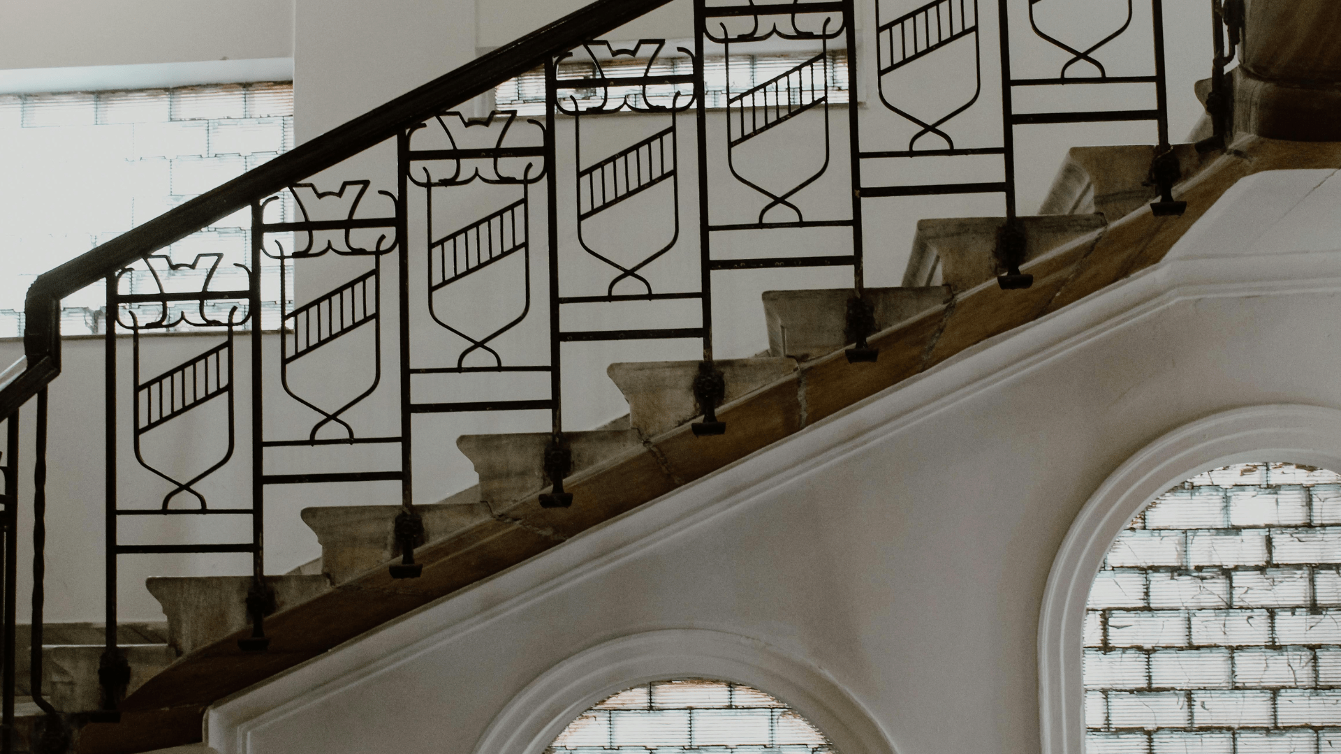 Barandilla de hierro en una escalera interior, con paneles decorativos geométricos y pasamanos negro.